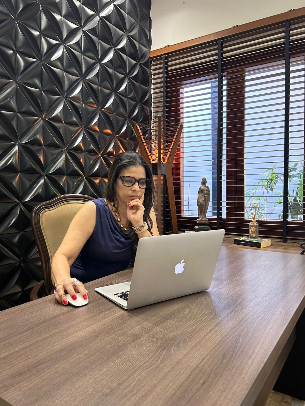 Carla em sua sala de atendimento, à mesa de trabalho